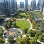 50 New Urban Parks: Greener Local Spaces Transforming Communities Aerial view of a bustling new urban park with green lawns, paths, trees, and city buildings.