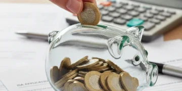 Hand placing coins into a piggy bank, representing UK savings under new ISA allowance rules