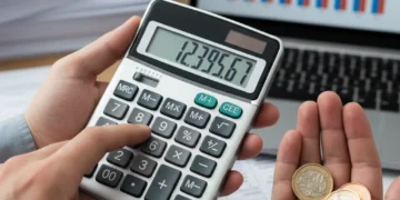 Hands calculating UK benefits increase with pound coins